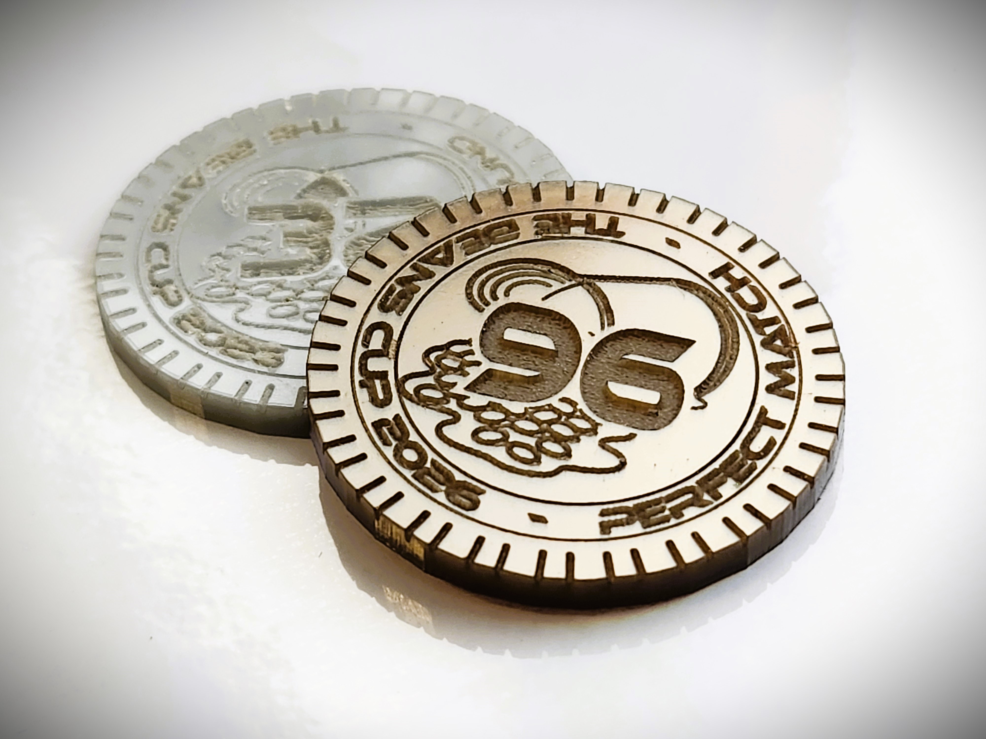 a golden 96 coin laying on-top of a silver 32 coin